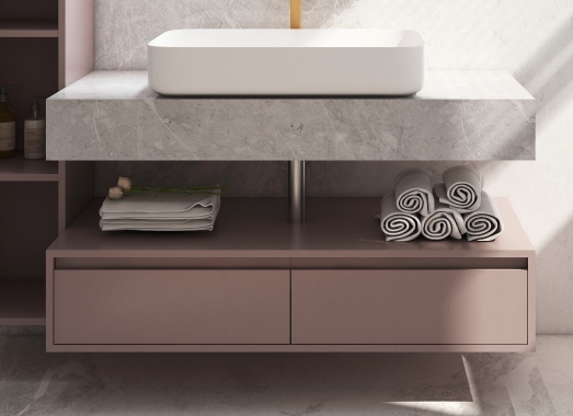 Modern vanity with round mirror and pink tones.