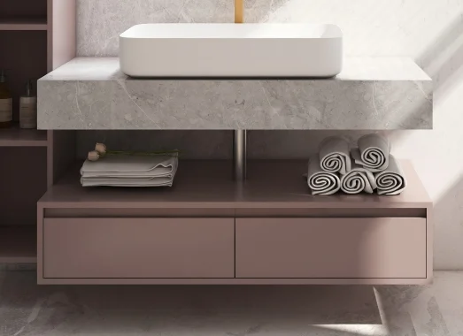 Modern vanity with round mirror and pink tones.