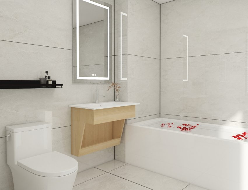 Bright bathroom featuring a modern floating vanity in light wood with a white countertop, set against minimalist beige tiles and highlighted by an illuminated rectangular mirror.